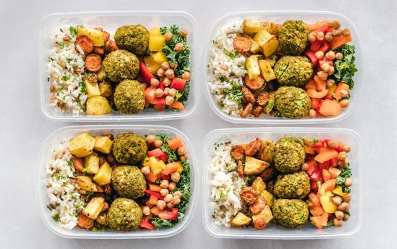 Colorful meal prep containers with falafel, chickpeas, rice, and vegetables for a healthy lifestyle.